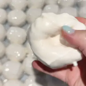 Smooth white squishy ball on desk with small white balls in background
