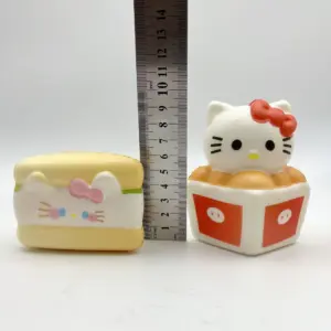 Miniature dessert-themed cat toy figures arranged on white risers with a metal ruler showing mm markings