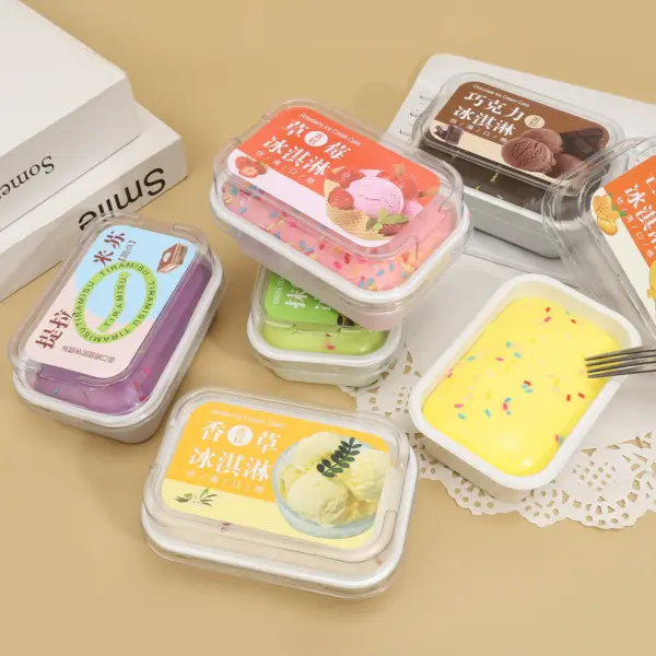 Rounded rectangular white tub filled with soft pastel yellow ice cream cake squishy, topped with rod-shaped multicolor sprinkles and a clear lid.
