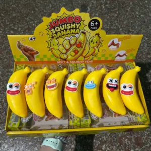 Hand holding a banana-shaped toy with one large open eye and a winking orange-lid eye