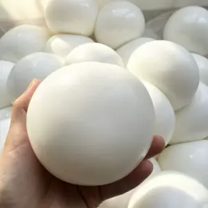 Smooth white sphere held in a human hand showing glossy surface