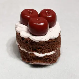 Glossy cherry toppings with stems on a miniature dessert figurine