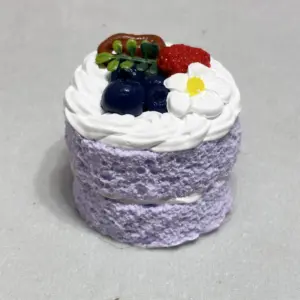 Miniature cake topped with blueberries, raspberries, and mango cubes